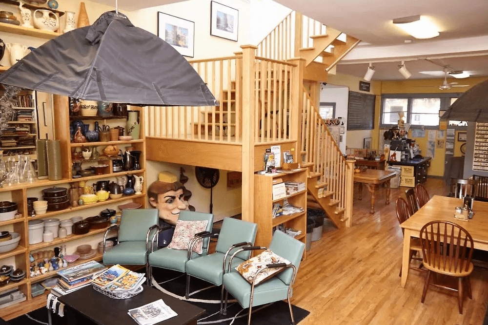 A cozy, eclectic space featuring a seating area, staircase, and shelves filled with various decorative items.