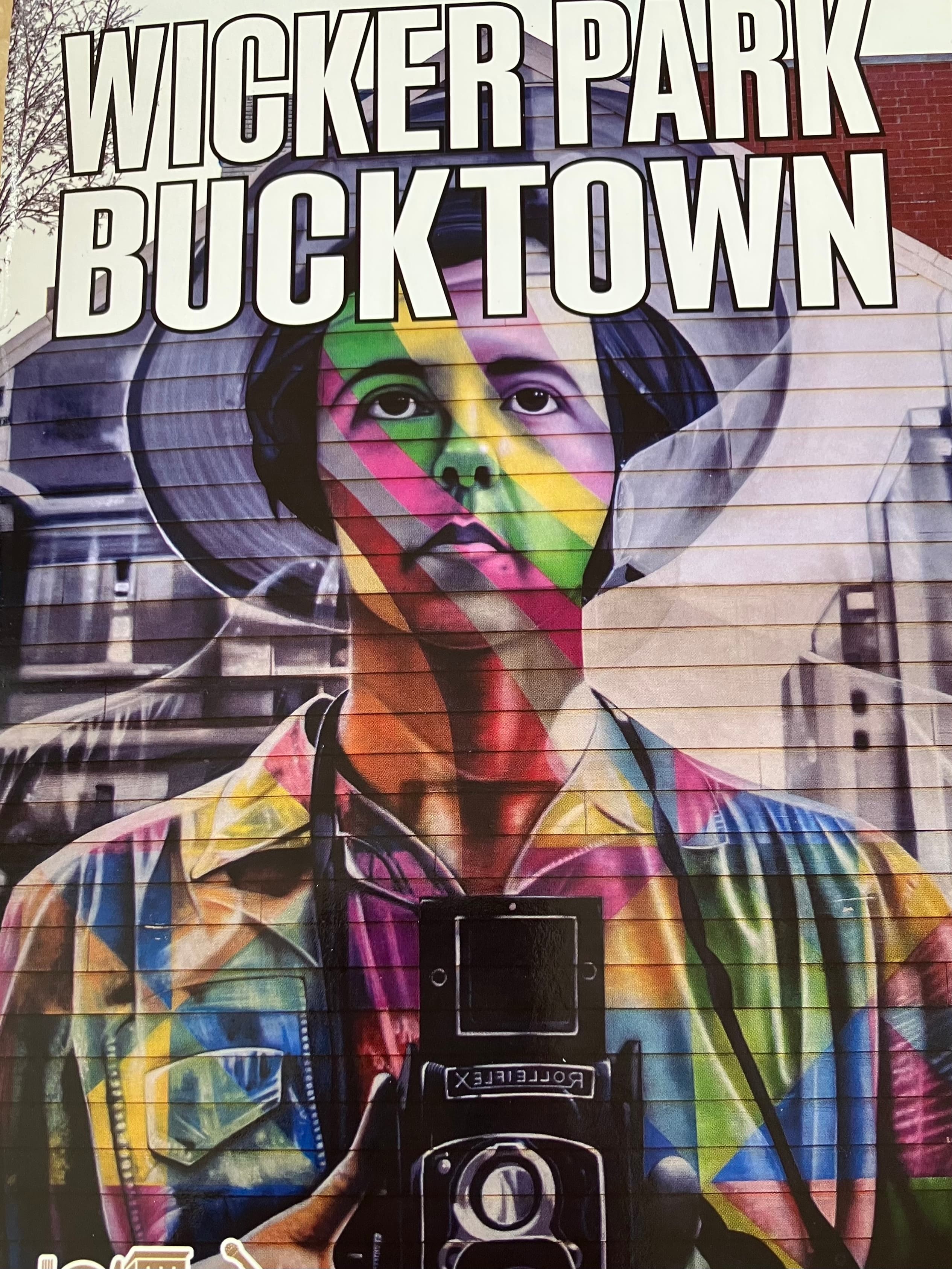 A colorful mural of a person holding a camera, with the words "Wicker Park Bucktown" displayed prominently above. A colorful mural of a person holding a camera, with the words "Wicker Park Bucktown" displayed prominently above.